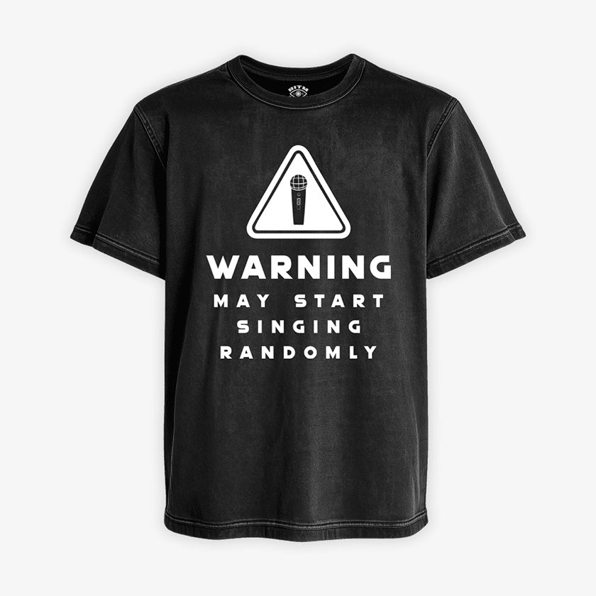 Polera Acid de color negro gastado. Diseño frontal con icono de advertencia y el texto en inglés "WARNING MAY START SINGING RANDOMLY"