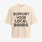 Polera color arena, corte oversized, con el diseño "Apoya Tus Bandas Locales" en negro. La mano hace el gesto de cuernos de rock