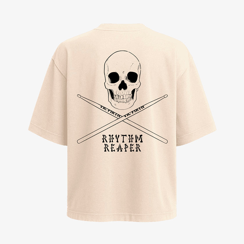 Polera color arena de corte oversized (holgado). Diseno pequeno de craneo y baquetas al frente. Diseno grande de craneo, baquetas y texto "Rhythm Reaper" en la espalda 2
